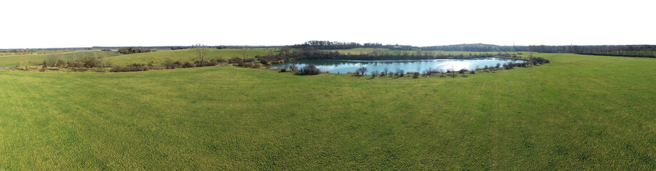 panoramic view over bright green grass field landscape with inbeded pond with blue water and sky is isolated on white or transparent png