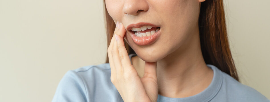 Face expression suffering from sensitive teeth, Asian young woman touching cheek