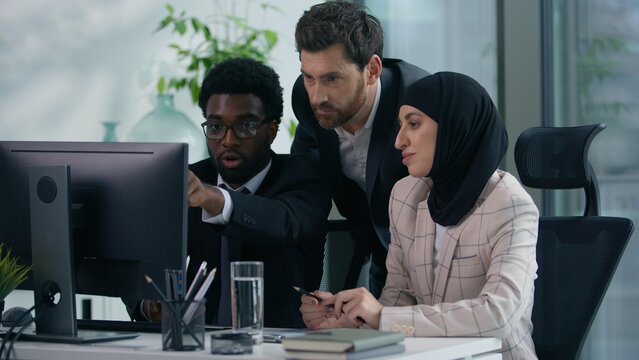 Multicultural business colleagues teamwork in office multiracial three co-workers working together diversity partners businesspeople talking pointing in computer meeting brainstorming work process