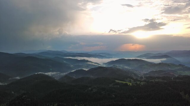 Cloudy weather over hills covered with spruce forests in Rhodope Mountains and fog between mountain ranges