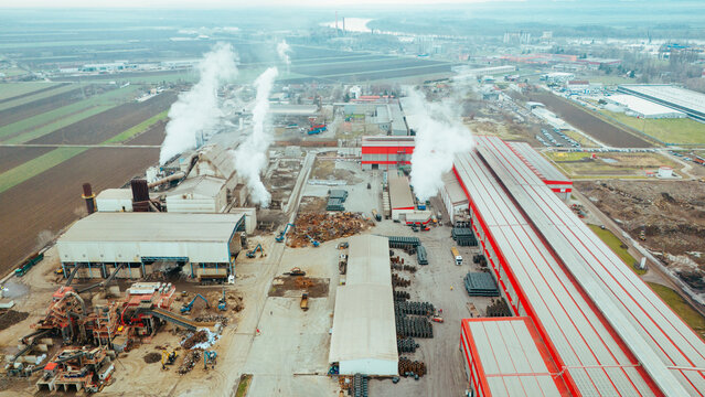 Aerial view of plumes of smoke rise from the industrial area, contrasting against the agricultural fields, Sremska Mitrovica, Vojvodina, Serbia.