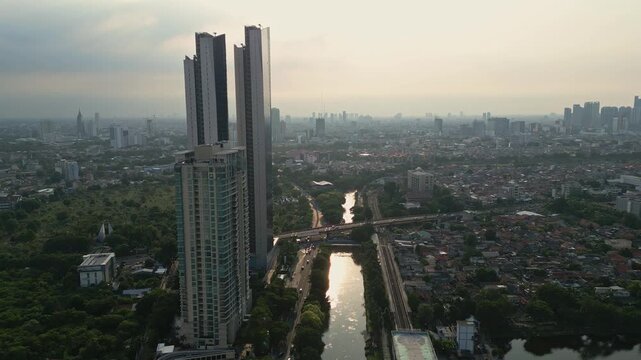 Jakarta, Indonesia: Aerial drone footage of modern skyscraper, luxury hotel and condominium towers along the Ciliwung river at sunset in the Jakarta business district in Indonesia capital city. 