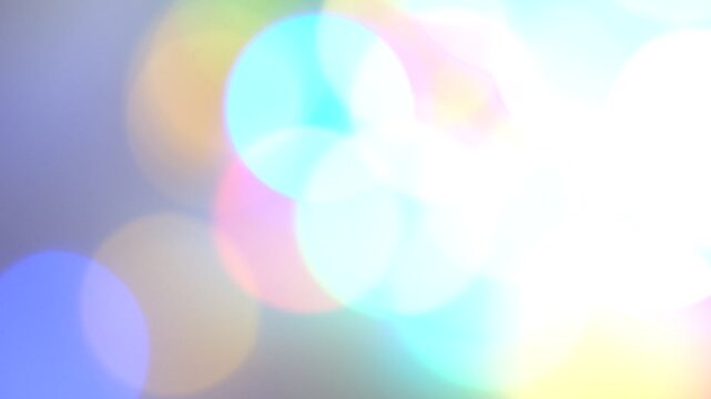 Multicolored glittering abstract rainbow flares bokeh background. White, blue, pink, green. Blurry abstract fairy light background with bokeh. Caustic light, refraction.