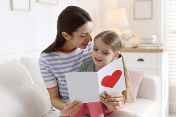 Happy Mother's Day. Little girl greeting her mom with holiday card on sofa indoors