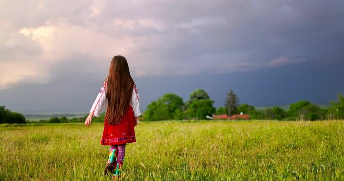 Beautiful Bulgarian Girl In Traditional Ethnic Embroidered Bulgarian Folk Costume in the countryside meadow