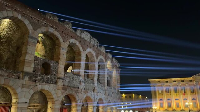 Night view of Verona&rsquo;s Arena di Verona, ancient amphitheater lit by spotlights forming thin beams, creating an illusionary image, historic landmark, atmospheric cityscape