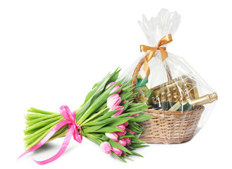 Festive basket with wine, gift boxes, candies and bouquet of flowers on white background