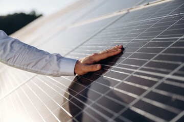 Touching the clean surface. Male solar engineer examining photovoltaic panels at a power station
