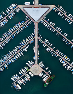 Aerial view of boats docked in a geometric harbor, contrasting against the deep blue sea, creating a serene and orderly marine scene, Ashdod, South District, Israel.