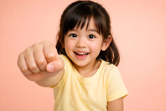 Excited little girl punching fist toward camera with forced perspective effect