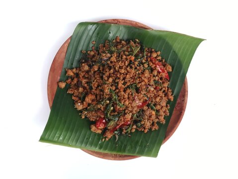 Indonesian stir-fried fermented soybean cake (Oseng Oseng Oncom) with banana leaf and wooden plate isolated on white background. Perfect for culinary, travel, and Asian food culture themes