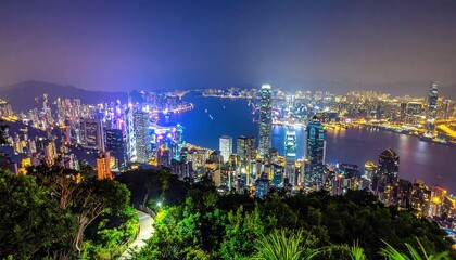 Aerial night view of a sprawling cityscape, with illuminated skyscrapers bordering a harbor