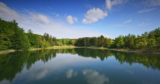 Reflections of trees in the Water Under Blue Sky And Fluffy White Clouds on a nice sunny day, panoramic nature  landscape Karandila mountain, Sliven, Bulgaria