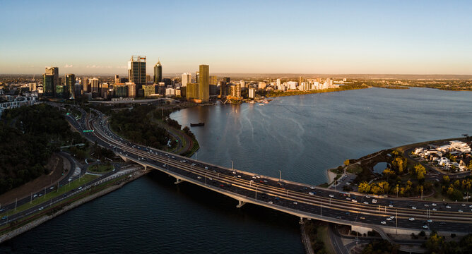 Aerial view of the bridge over the Swan River leading to Perth's skyline, with golden light reflecting off the water, Kings Park Perth, Western Australia, Australia.