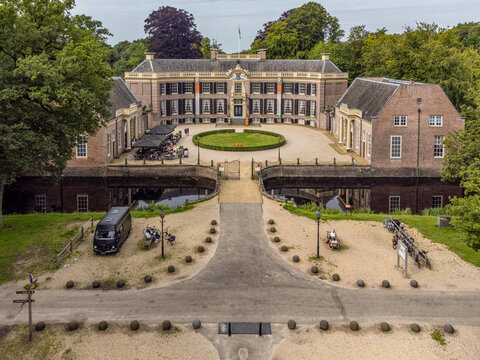 Aerial view of the grand Kasteel Groeneveld, its brick facade contrasting with the lush green lawns and surrounding trees, Baarn, Utrecht, Netherlands.