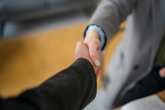 Two business professionals shake hands, signifying agreement and partnership in a professional setting.