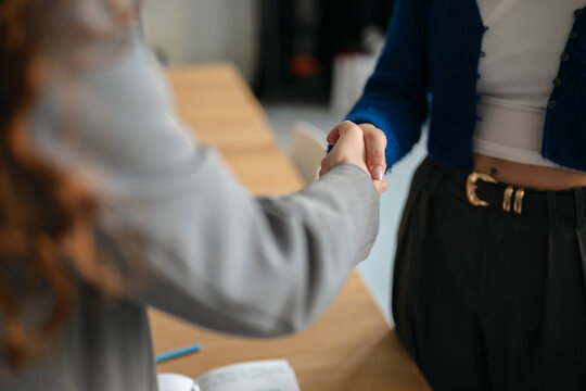 Two people shake hands over a desk, signifying agreement or a successful negotiation.