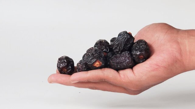 Hand giving a dates fruits or kurma to other hand. Isolated focus. 
