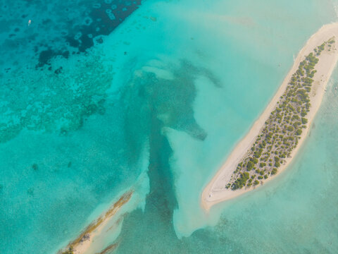 Aerial view of turquoise waters embrace the sandy Kan island, with its crescent shape kissed by the sun, Dhidhdhoo, Thiladhunmathi Atoll, Maldives.