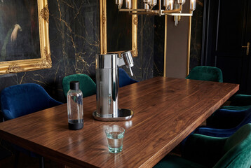 Chrome metal soda maker on wooden table in luxury dining room