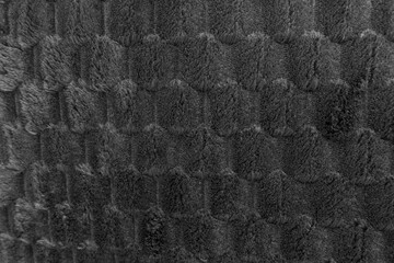 Dark gray textured plush fabric background with a soft, cozy, and geometric bumpy pattern © reddish