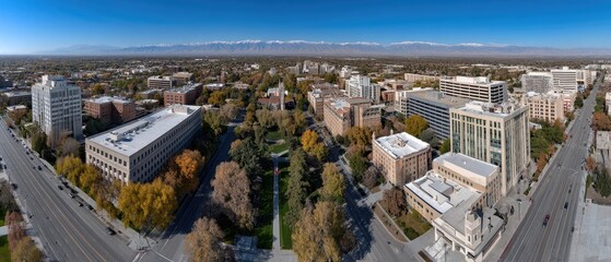 A university campus and church with colorful autumn trees under a clear blue sky. Mountains frame the scene
