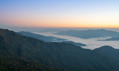 Soft morning light over layered mountains and mist creating a peaceful natural scene.