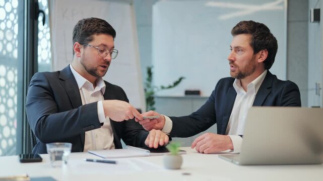 Business professionals finalize significant money deal in modern office, exchanging cash and sealing agreement with firm handshake. Demonstrates trust, satisfaction, reflecting successful negotiation.