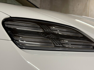 Detailed shot of a white car's headlight, highlighting its design and modern technology. Perfect for automotive and tech