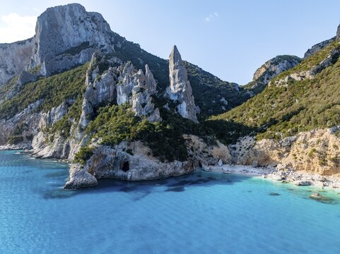 Picturesque rocky coast, cliffs with L'Aguglia pinnacle, blue sea and Cala Goloritz&eacute; beach, aerial view, Golfo di Orosei, Baunei, Sardinia, Italy