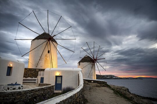 Illuminated windmills, Kato Milli, at sunset, dramatic cloudy sky, Mykonos Town, Mykonos, Greece