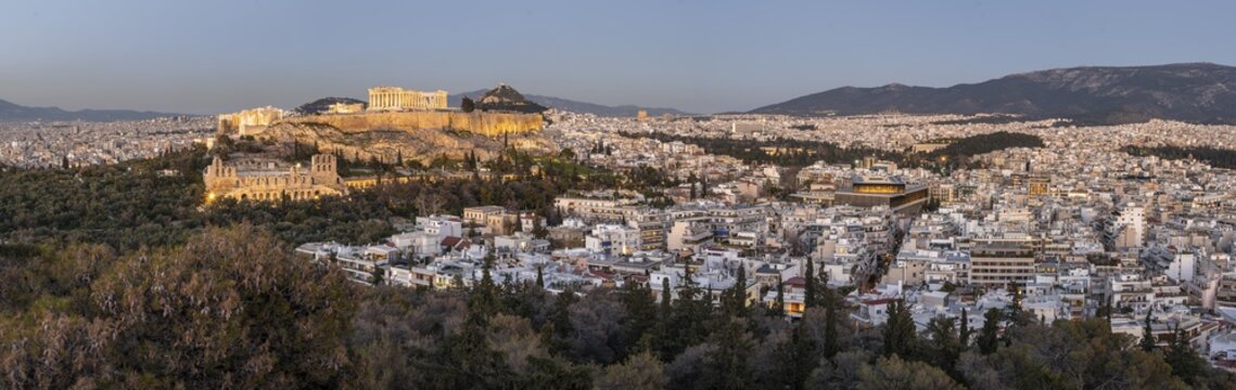 View from Philopappos Hill over the city at sunset, panorama of the illuminated Parthenon Temple and Herod's Amphitheatre, Acropolis, Athens, Greece