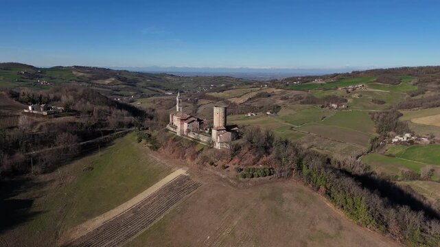 Castello di Monteventano fortified complex with church tower dominating countryside near Piozzano, Province of Piacenza, Emilia-Romagna, Italy, rural hilltop landscape revealed in aerial view.