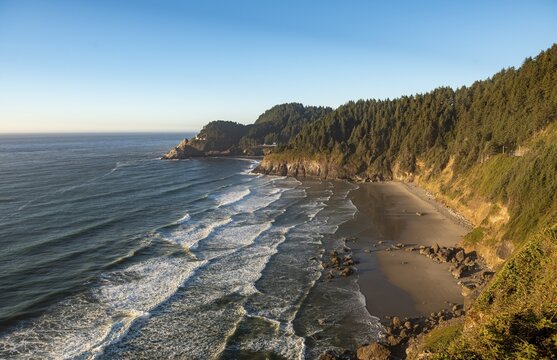 Sandy beach Sealion Beach with Devils Elbow, in the back rocky coast with Heceta Head lighthouse, Oregon, USA