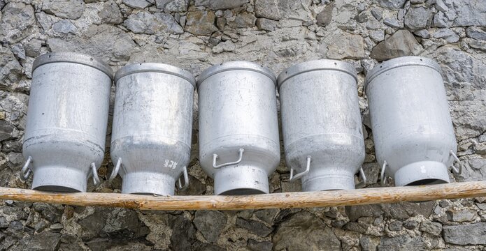 Milk cans lined up on a wooden bench, fa&ccedil;ade made of rough stones of an alpine pasture, Gramaialm, Alpenpark Karwendel, Tyrol, Austria