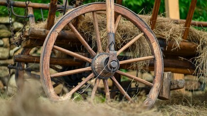 Close-up of a historical wooden wagon wheel with hay in a rural setting © Igor