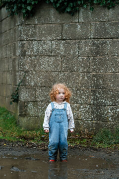 A girl with a serious look standing in a puddle in rural Ireland