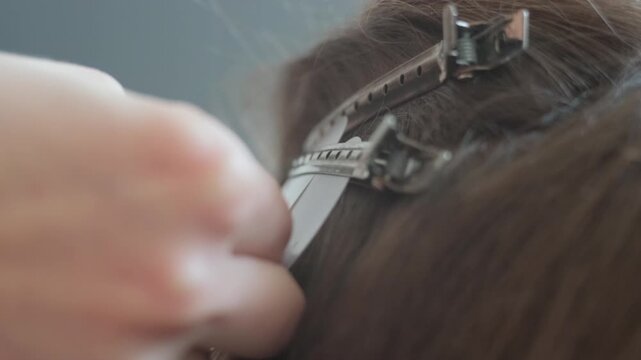 Professional hair stylist hands carefully sorting and sectioning brown hair for a professional extension procedure