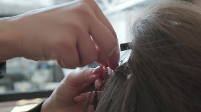 Professional hair stylist hands carefully sorting and sectioning brown hair for a professional extension procedure