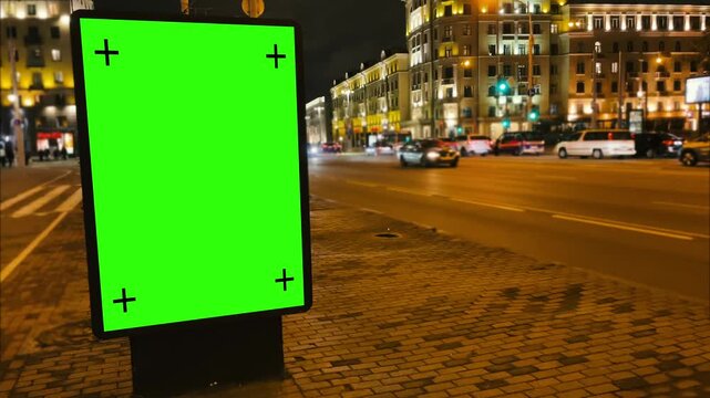 Green screen mockup concept. Nighttime shooting of an evening city street with a billboard on a green screen with tracking markers to add custom digital advertising or promotional content. 4k footage