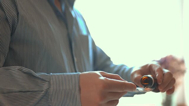 Man pouring liquid cough syrup into a spoon, medication dosage and healthcare concept.