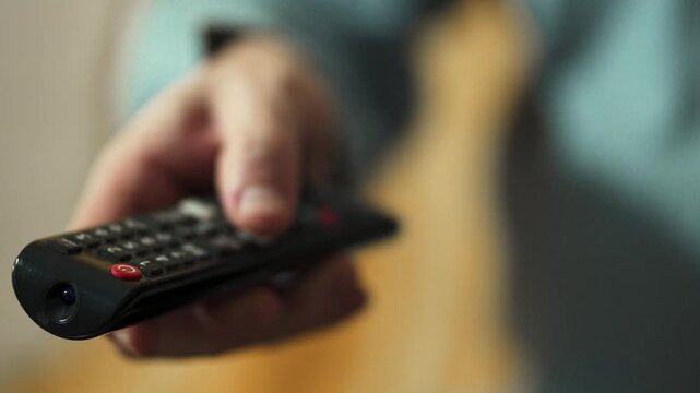  Close-up of Hand Switching TV Channels with Remote Control.