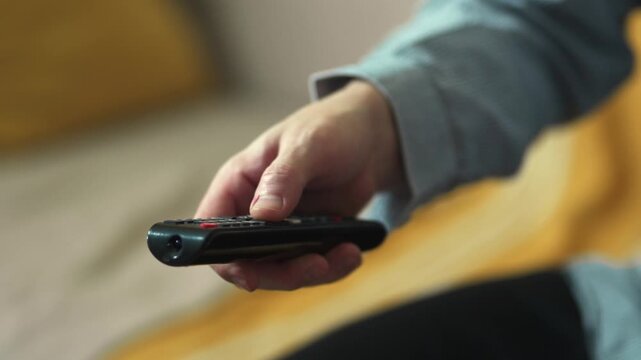  Close-up of Hand Switching TV Channels with Remote Control.