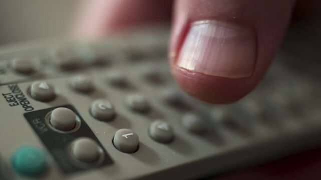  Close-up of Hand Switching TV Channels with Remote Control.