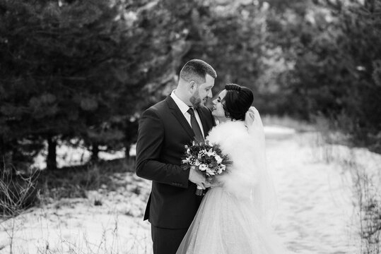 young couple, the bride and groom, taking a winter walk in forest