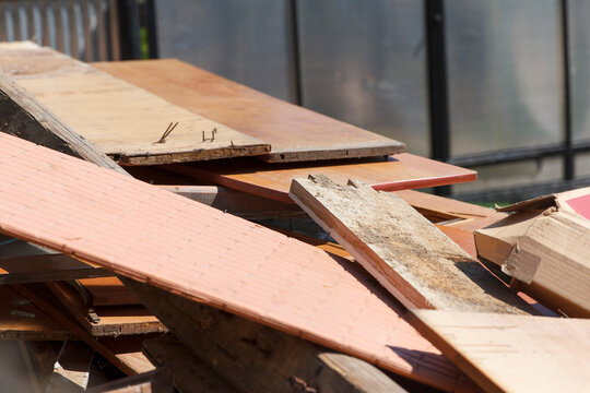 Pile of old wooden planks, discarded furniture parts, and construction debris outdoors.