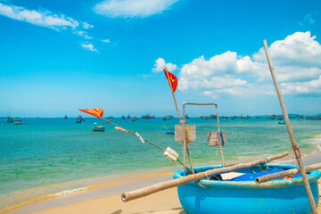 Fototapeta premium Traditional fishing shoreline with round basket boat and Vietnamese flafs on sandy tropical beach with turquoise water sea on Phu Quoc island, Vietnam. Vietnamese fishing culture