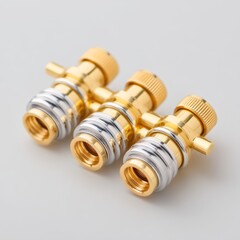 Three Elegant Brass and Silver Plumbing Valves with Shine and Detail on Soft Gray Background