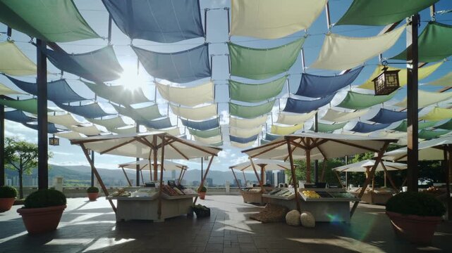 Beach umbrellas and lounge chairs under colorful fabric canopies on a sunny day by the ocean
