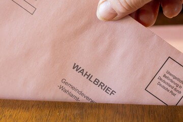 Naklejka premium Briefwahl Symbolbild: Ein Wahlbrief wird in die Wahlurne einer Gemeindeverwaltung geworfen